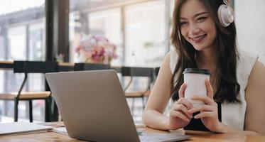 jovem empresária asiática linda e encantadora sorrindo segurando uma xícara no escritório foto