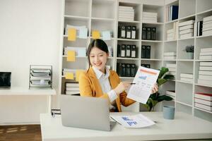 mulher asiática confiante com um sorriso em pé segurando o bloco de notas e tablet no escritório moderno. foto