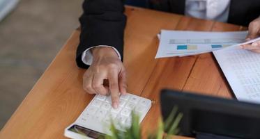 mãos de mulher de negócios com calculadora no escritório foto