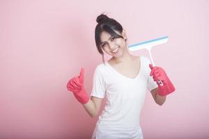 linda dona de casa asiática sorrindo em fundo rosa foto