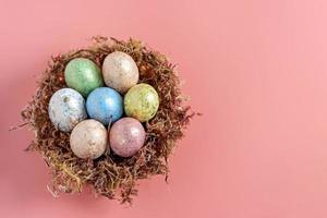 ovos de Páscoa em um ninho natural com musgo em um fundo rosa. vista de cima
