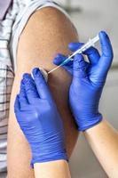 um médico vacina um homem contra o coronavírus em uma clínica. fechar-se. o conceito de vacinação, imunização, prevenção contra covid-19. foto