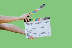 mão segurando quadro de cores de ardósia de filme para a indústria de cinema e televisão sobre fundo verde