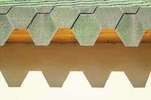 telhado verde com telhas hexagonais. telhado com bordas irregulares lançando sombras duras na parede. foto