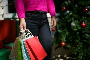 feliz ásia menina aguarde compras bolsas natal presente. alegre mulher com Natal Novo ano inverno venda foto