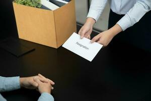 o negócio mulher enviando renúncia carta para patrão e segurando coisa demitir-se deprimir ou carregando cartão caixa de escrivaninha dentro escritório foto