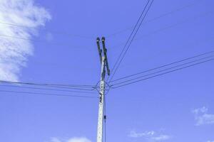 elétrico postes com elétrico cabos e poder linhas em uma Claro céu fundo foto