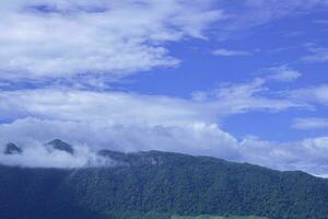 lindo natureza Alto montanhas Visão nuvens azul céu fundo às campo do panorama Colina foto