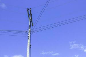 elétrico postes com elétrico cabos e poder linhas em uma Claro céu fundo foto