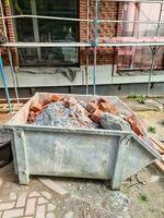 uma recipiente com destroços, Pedregulho dentro frente do uma construção local. foto
