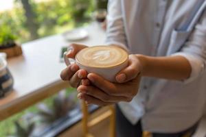 mão de uma mulher segurando uma xícara de café na cafeteria foto