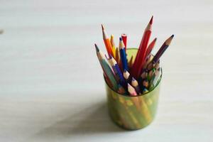 multicolorido de madeira lápis dentro plástico copo mesa. foto