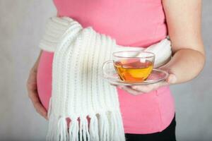jovem grávida mulher mantém vidro copo do ervas chá. foto
