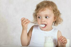 pequeno menina come natural açúcar livre iogurte. fechar-se foto