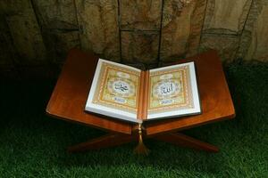 muçulmano piedosos livro Alcorão dentro a mesquita, Alcorão em uma de madeira borda com Relva fundo foto