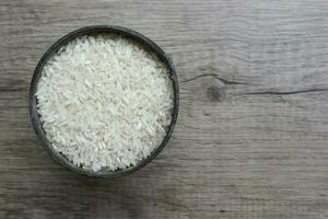 branco arroz, arroz dentro a ferro recipiente em a de madeira fundo foto