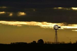 panorama com moinho de vento às pôr do sol, pampas, Patagônia, Argentina foto