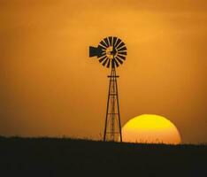 moinho de vento dentro a campo, às pôr do sol, pampas, Argentina foto