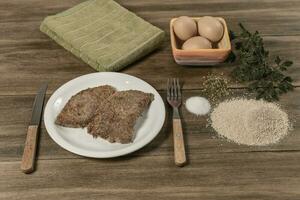 vitela a milanesa apresentado em a mesa com ingredientes foto