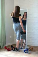 jovem mulher olhando às dela reflexão dentro a espelho, tentando em sapatos foto