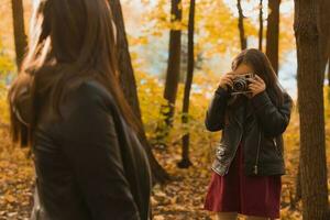 criança menina fotógrafo leva As fotos do uma mãe dentro a parque dentro outono. hobbies, foto arte e lazer conceito.