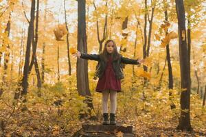 ásia criança menina jogando dentro a outono em a natureza andar ao ar livre foto