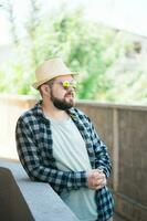 barbudo homem retrato dentro verão roupas e chapéu ficar de pé sobre rua cidade urbano e viagem conceito foto