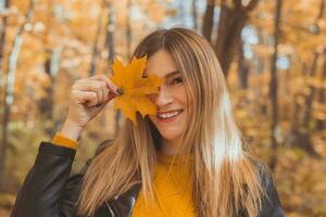 jovem mulher com outono laranja bordo folha sobre outono estação fundo foto