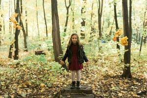 ásia criança menina rindo e jogando dentro a outono em a natureza andar ao ar livre foto