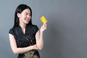 Mulher asiática usando vestido tradicional chinês com a mão segurando um cartão de crédito