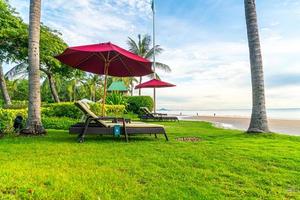 guarda-chuva com cadeira com fundo de praia de mar e nascer do sol pela manhã foto