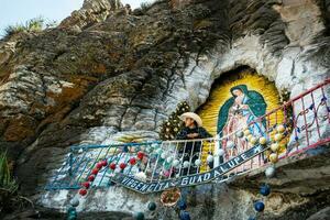 homem visitando virgem do guadalupe pintura em pedras dentro México foto