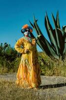 mexicano mulher dentro colorida vestir e crânio Maquiagem dentro a mexicano deserto cacto foto