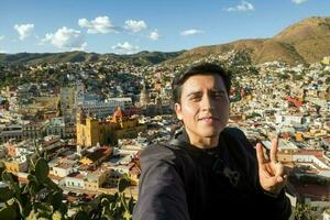 uma homem captura uma selfie dentro a vibrante cidade do guanajuato, México, com tirar o fôlego montanhoso paisagens dentro a fundo foto