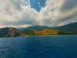 Visão a partir de a mar para a montanhas e a azul céu com nuvens foto