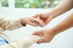 cuidador de mãos dadas paciente idosa asiática, ajuda e cuidados no hospital. foto