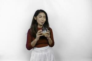 a ásia menina vestindo uma vermelho camiseta é desfrutando e bebendo dela café, isolado em branco fundo foto