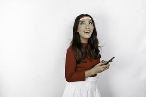 uma retrato do uma sorridente ásia mulher vestindo arco de cabelo e segurando dela telefone, isolado de branco fundo. da indonésia independência dia conceito foto