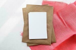 a envelope fez do kraft papel e uma branco em branco cartão em uma branco mesa foto