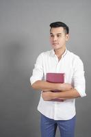 retrato de um estudante universitário segurando um livro no fundo cinza do estúdio foto