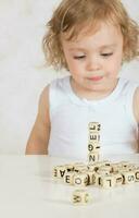 pequeno menina compõe palavras a partir de cartas. fechar-se foto