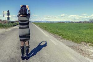 bonita mulher levando uma selfie dentro a meio do uma estrada foto