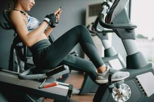 lindo ásia mulheres levar uma descansar jogando uma Smartphone depois de exercite-se às Academia foto