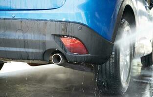 carro lavando com Alto pressão água spray. carro limpeza. auto Cuidado serviço conceito. veículo limpeza. Alto pressão água pulverização em carro roda e pneu. manual carro lavar com Alto pressão água. foto