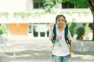 retrato do fofa pequeno menina com mochila caminhando dentro a parque. foto