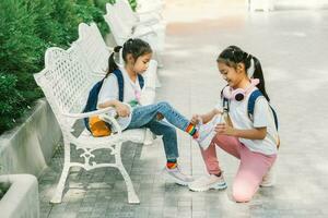 dois pequeno meninas sentado em a Banco dentro a parque foto