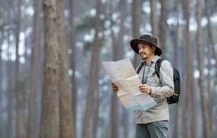 ásia naturalista olhando às a mapa para direção enquanto explorando animais selvagens dentro a pinho floresta para levantamento e descobrindo a raro biológico diversidade e ecologista em a campo estude conceito foto