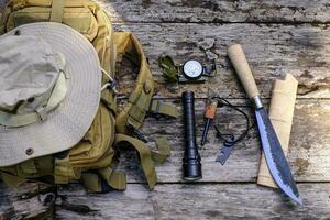 faca mochila com equipamento para sobrevivência dentro a floresta em a velho de madeira fundo foto