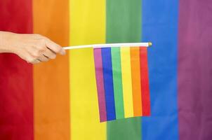 mão segurando colorida arco Iris gay bandeira, símbolo do lgbt pessoas, diversidade do sexos amor,romance, tolerância, celebração, conceito do lgbtq comunidade igualdade movimento, lgbt feliz orgulho mês foto
