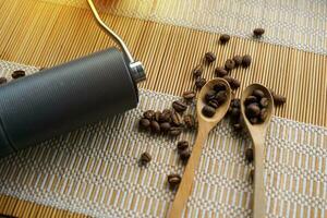 moedor e café feijões dentro uma de madeira colher em bambu esteira fundo para uma simples Preto café gotejamento de você mesmo e pessoas quem gostar especial aromas e sabores específico para este café feijão. foto